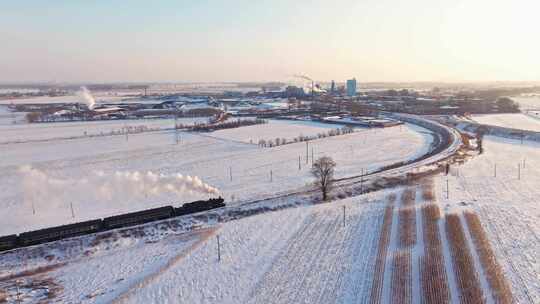 航拍中国东北冬季雪景中的蒸汽火车穿过村庄