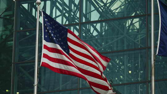 美国国旗在现代摩天大楼玻璃幕墙前挥舞视频素材模板下载