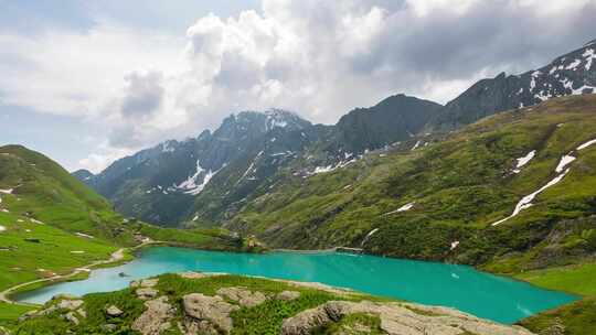 延时拍摄：意大利阿尔卑斯山上的山峰和翠绿色的高山湖泊，云层在移动