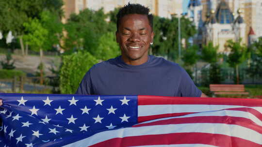 相机放大爱国者微笑的美国黑人手持美国国旗