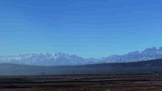 大气航拍西北戈壁滩上的公路及远方的雪山