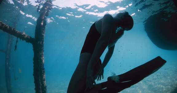 女子自由潜水员在蓝海水下游泳女子自由潜水