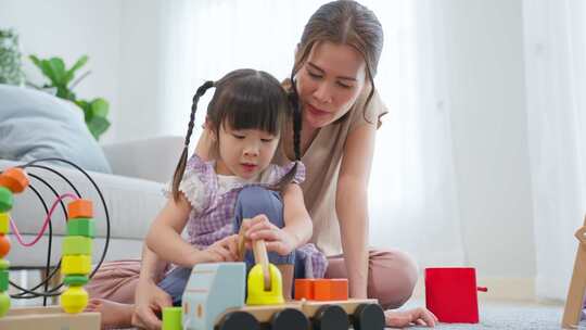 亚洲美丽的爱妈妈和女儿在家里玩教育游戏。