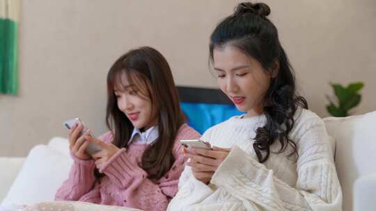两女性沙发上玩手机场景