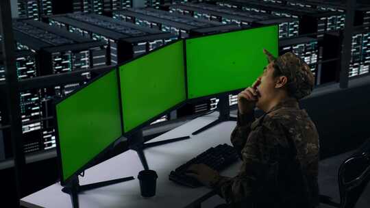 疲惫的亚洲军人在数据中心模拟多台电脑显示