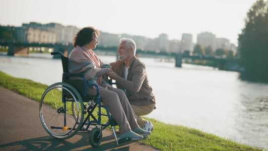 丈夫和妻子坐轮椅散步老年家庭夫妇在城市公