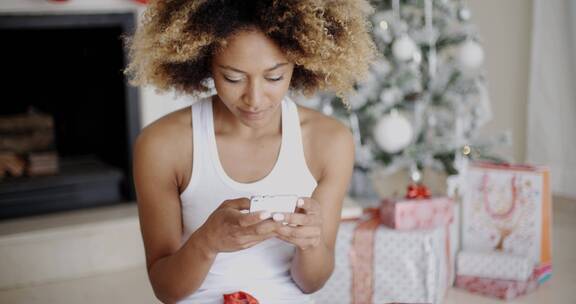 女人在圣诞树旁玩手机