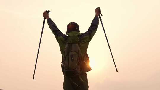 户外徒步者高举登山杖庆祝胜利