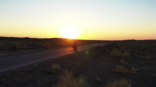 日落时分骑手在西部空旷的公路上骑摩托车