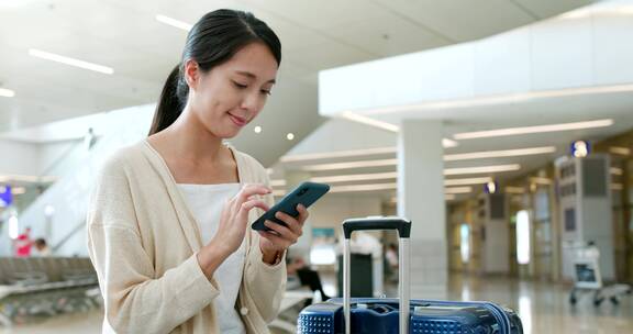 妇女在机场使用智能手机