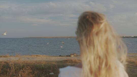 一个金发女人站在海岸边的背影