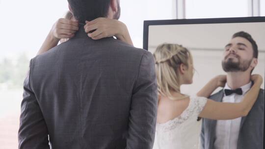 在镜子前新娘为新郎整理西服视频素材模板下载