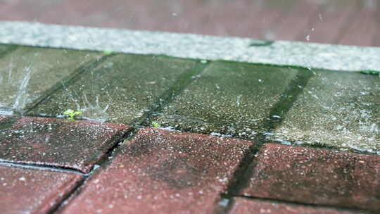 暴雨中雨滴在人行道地砖上溅起特写慢镜