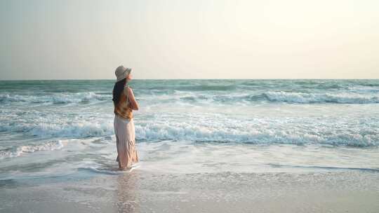 女人赤脚走在金色的日落海滩上