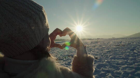 女孩站在雪地里比了一颗心