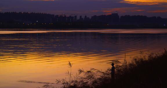 4k夕阳下江边钓鱼的男人