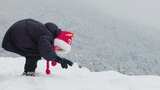 小孩雪地弯腰伸手玩耍高清在线视频素材下载