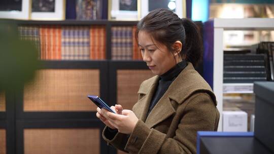 中年女性在书店书架前使用手机
