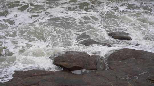 海浪拍打岩石浑浊海水冲刷礁石浪花阴天大海