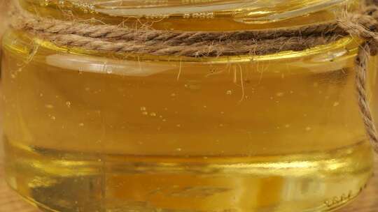 蜂蜜从勺子纺锤流入一罐柠檬水背景上的蜂蜜罐