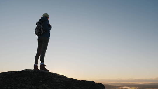 女旅行者站在山顶上看日出