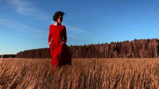 穿着猩红色连衣裙在风中流动的年轻女模特。