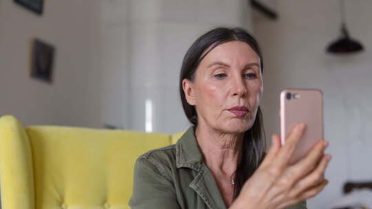 美国成熟的女士是有视频通话使用智能手机在公寓在自我隔离Spbi