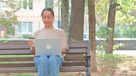 年轻女子在户外用信用卡享受网上银行