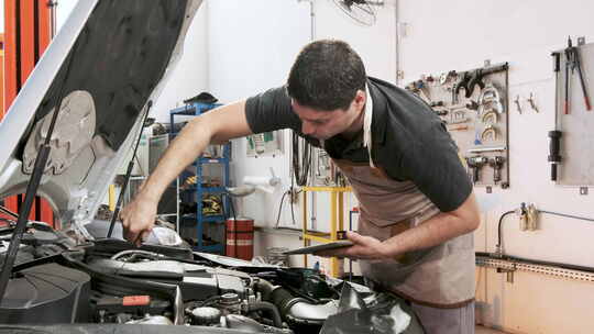 西班牙裔男性汽车机械师拿着剪贴板重新插入量油尺