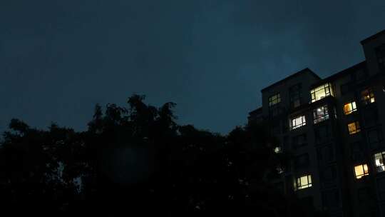 雨夜窗外的城市居民楼灯光和闪电