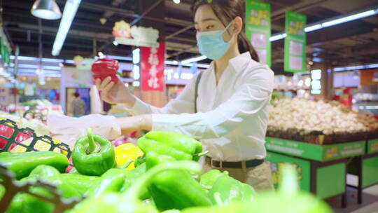 戴口罩的青年女人在超市选购蔬菜