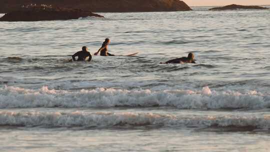 冲浪板上的冲浪者漂浮在岩石海岸线附近的海