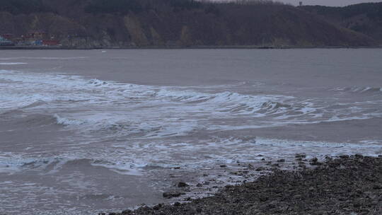 冬天下雪时候的海边海里海浪翻滚着