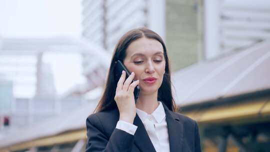白人年轻女商人在城市散步时用智能手机聊天。迷人美丽的女性