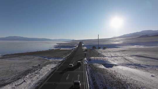 航拍冬季新疆赛里木湖环湖车辆行驶雪山公路
