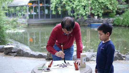 老人教小孩户外写毛笔字