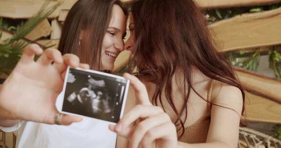 快乐的女同性恋女性在爱情中，期待婴儿和显