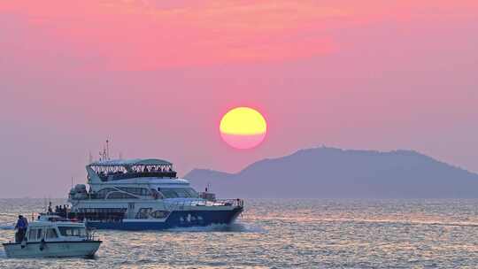 海南三亚橘红色夕阳晚霞行驶的巨型豪华游艇