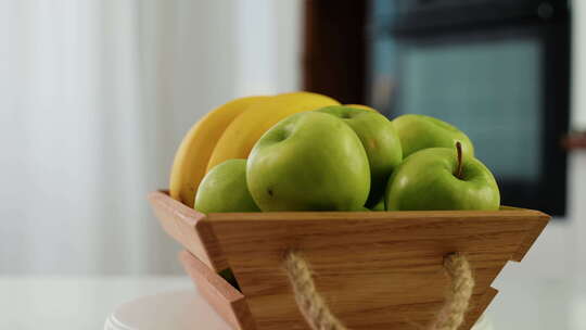木制篮子，新鲜香蕉和苹果在厨房水果静物上