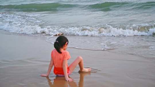 海南三亚坐在沙滩上快乐玩水的可爱女孩