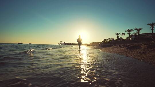 小男孩在日落时分的海滩奔跑