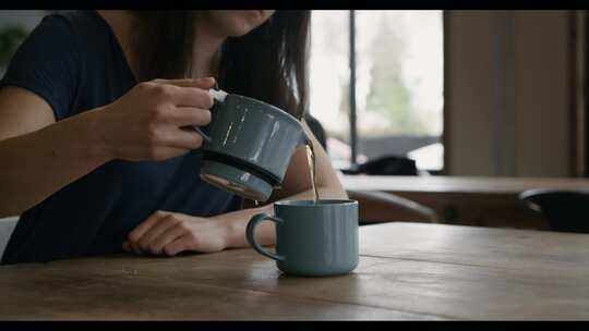 咖啡店里，女人把茶倒进杯子里