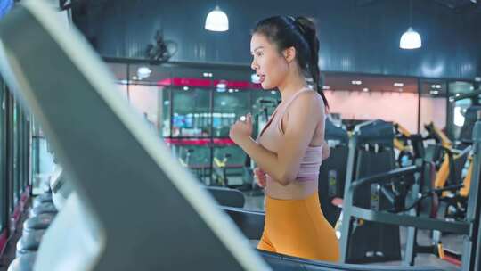 健身房跑步机上穿着运动服跑步的运动女孩视频素材模板下载