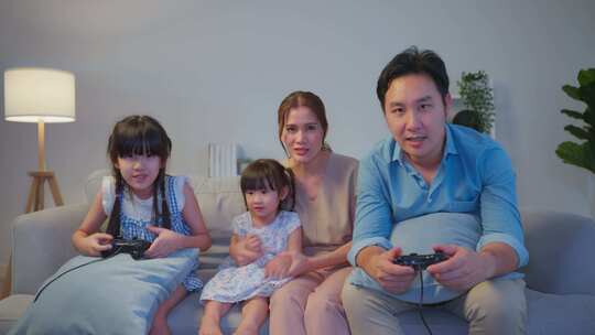 亚洲幸福的家庭晚上一起在客厅玩游戏机游戏。