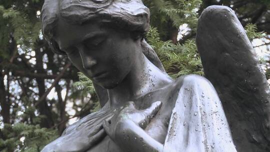 天使的雕像矗立在墓地的坟墓上