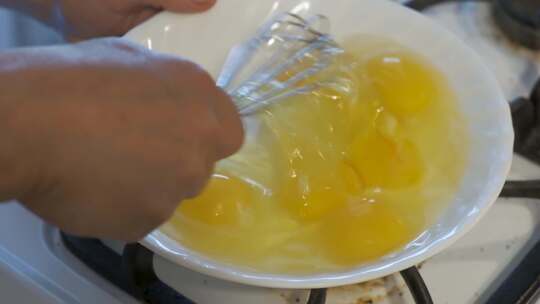 女人用搅拌器慢动作在白色碗里炒鸡蛋视频素材模板下载