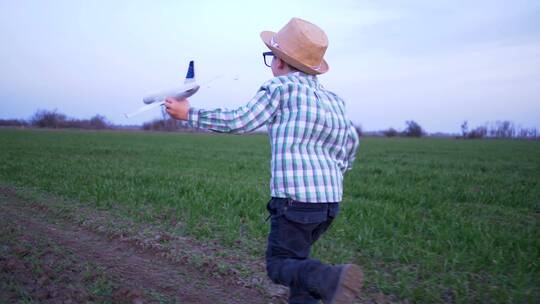 拿飞机模型在田地奔跑的男孩