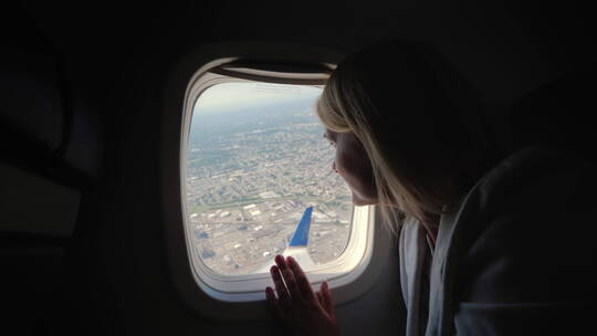 一名女乘客从飞机的窗户望向大都市下方的地面