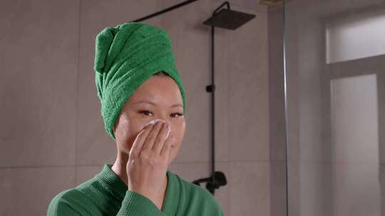 开朗可爱的中年亚洲女人用棉垫清洁面部皮肤