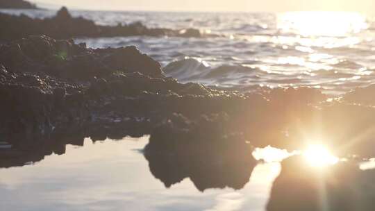 太阳光照亮海水汹涌拍打岩石